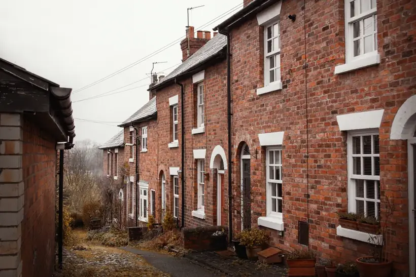 Terrace of red brick British houses with guttering and downpipes along a residential street