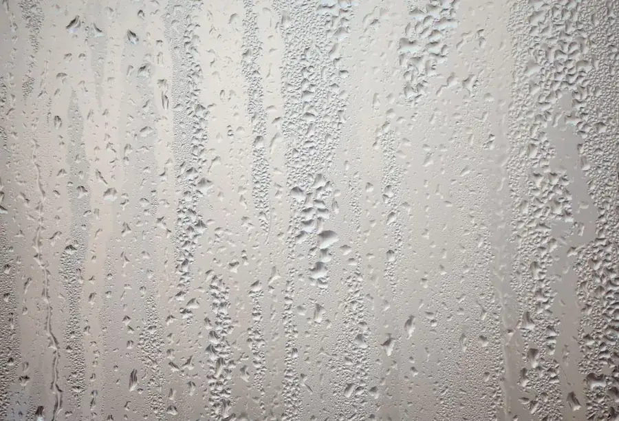 Heavy condensation streaking down a pane of glass in cold weather
