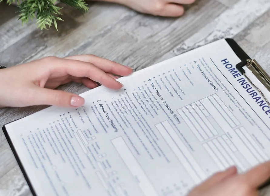Hands holding a home insurance policy document at a table