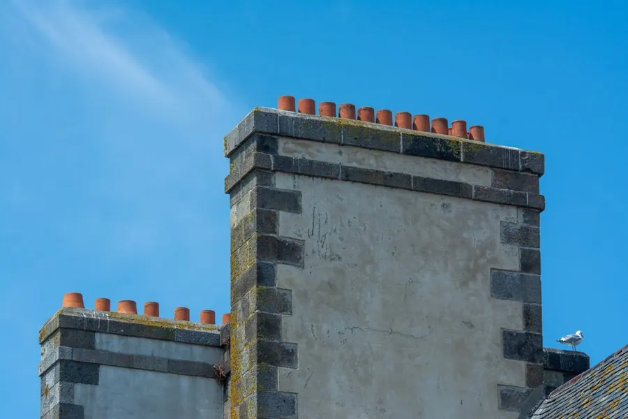 Stone chimney stacks with terracotta pots on a period roof