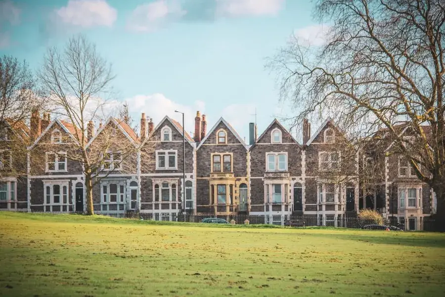 Row of Victorian stone terraced houses with steep gabled roofs facing open parkland