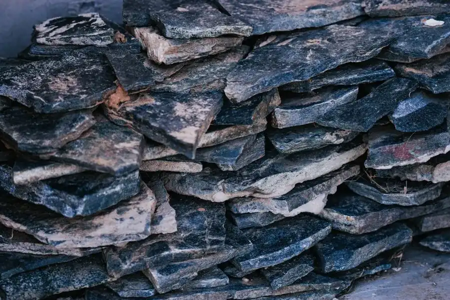 Stack of irregular flat grey stone slates piled up ready for sorting and re-laying