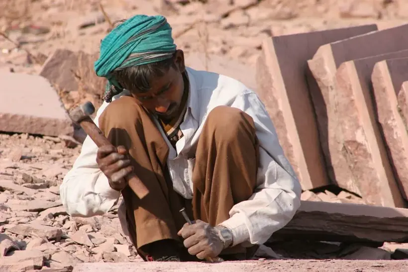Craftsman's hands working stone with traditional hand tools
