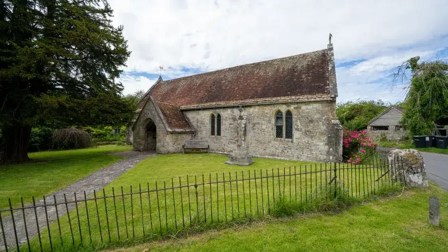 English village church with an old stone roof laid in irregular courses under a cloudy sky