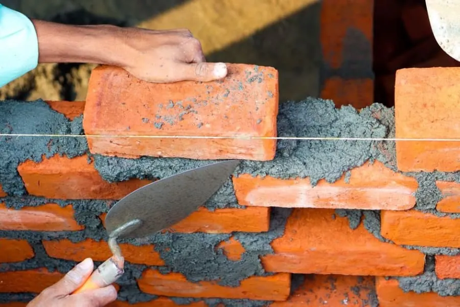 A roofer repointing the brickwork on a chimney stack