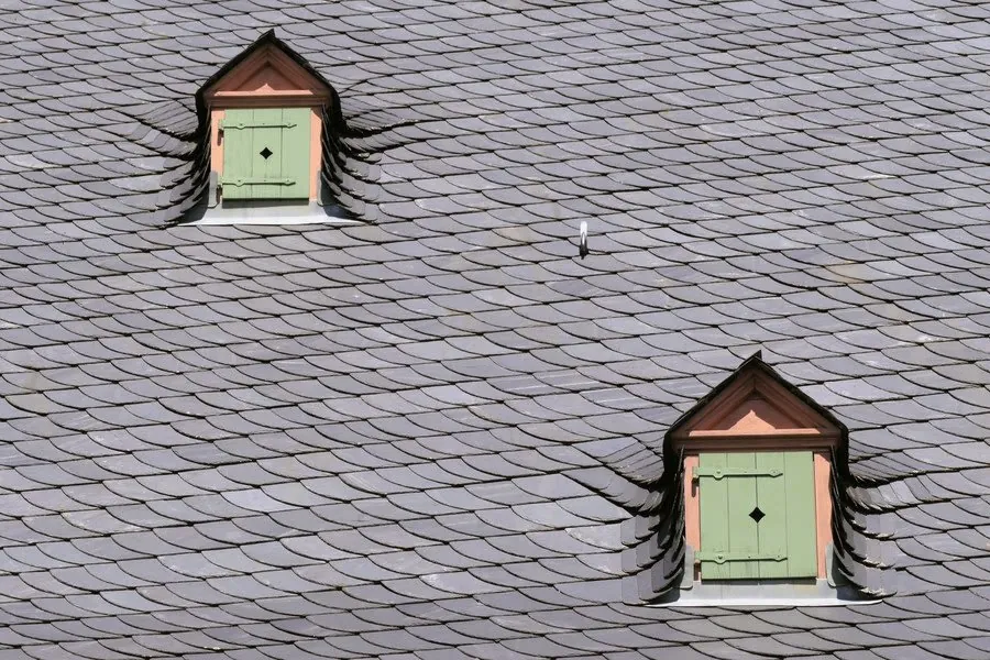 A slim roof window set into a slate roof