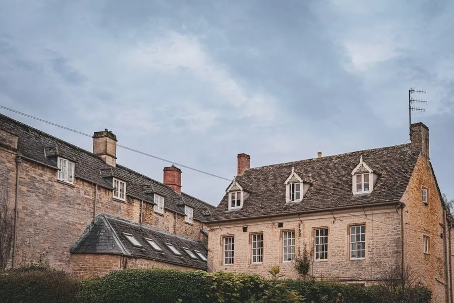 Historic stone buildings with dormer windows under a cloudy sky