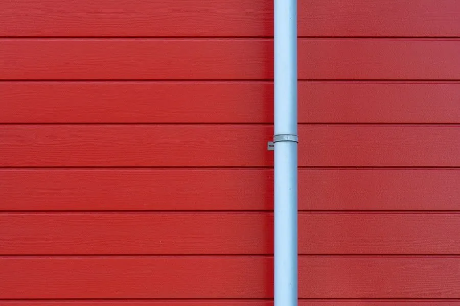 Red wooden wall with a vertical light gray pipe in the center