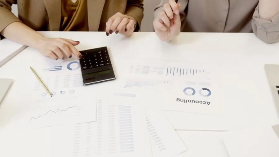 Two people reviewing service charge figures and estimates with a calculator