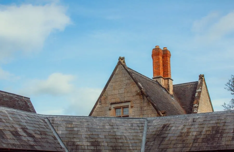 A grand old stone building with a natural slate roof