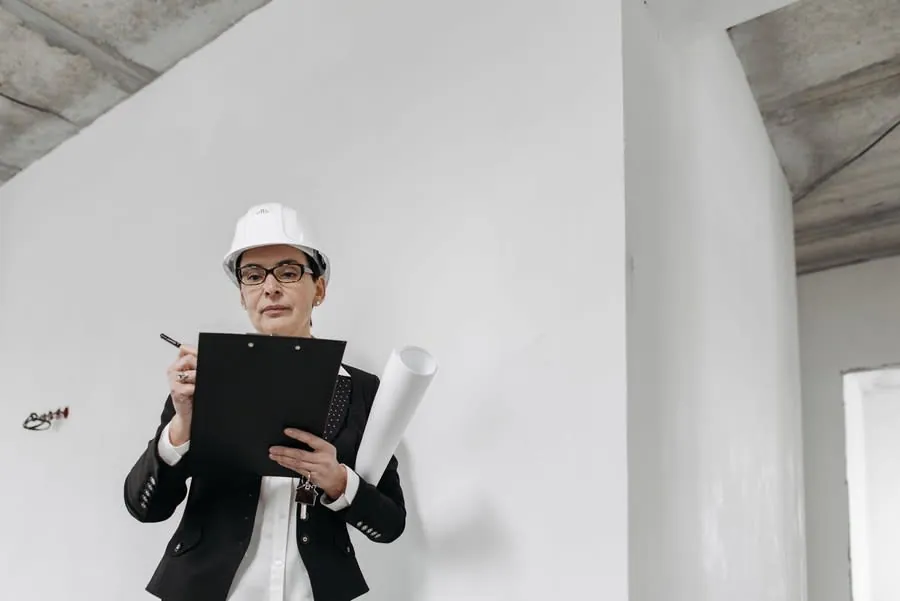 Architect in hard hat reviewing blueprints in a bright unfinished room