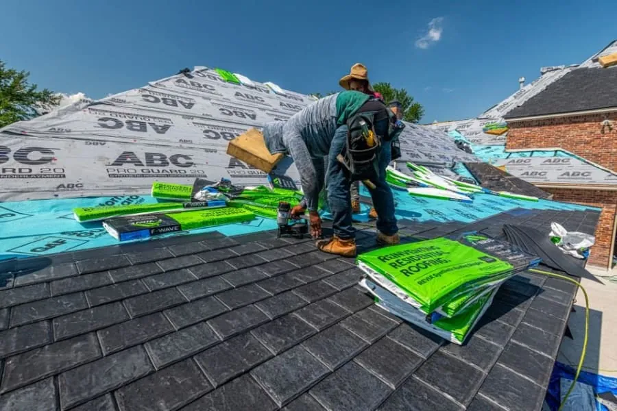 Roofers re-laying slates alongside a newly lined roof valley