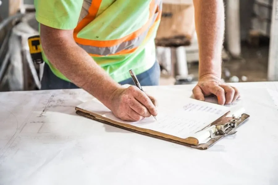 A roofer writing up an itemised assessment on a clipboard