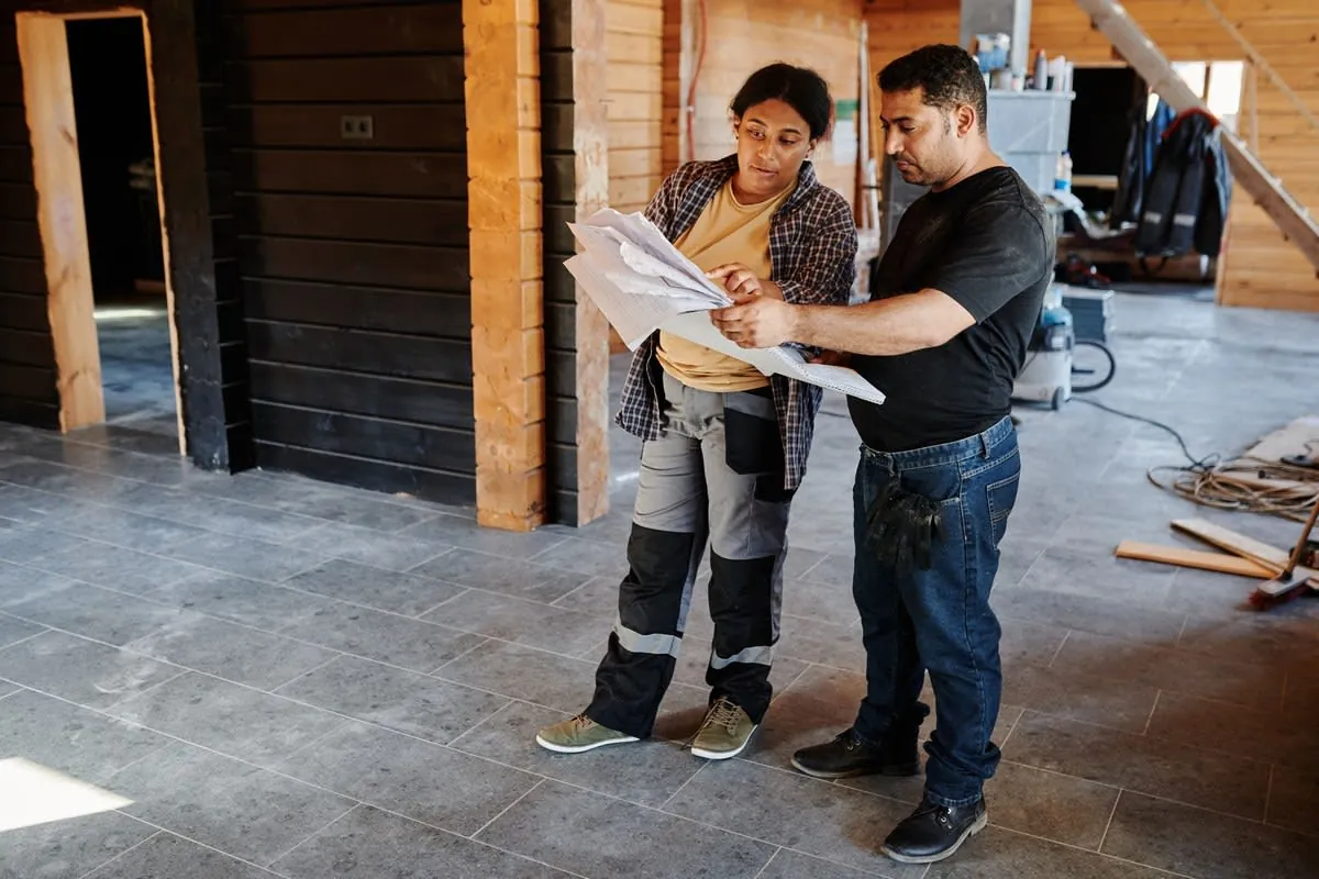 Two people reviewing plans in an unfinished building interior