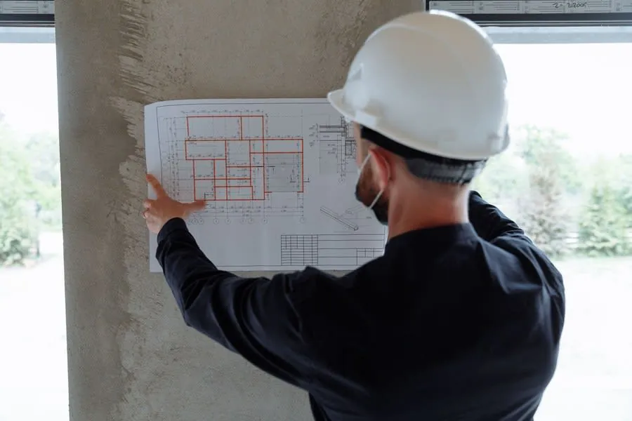 Construction worker in a hard hat reviewing blueprints on a wall at a building site