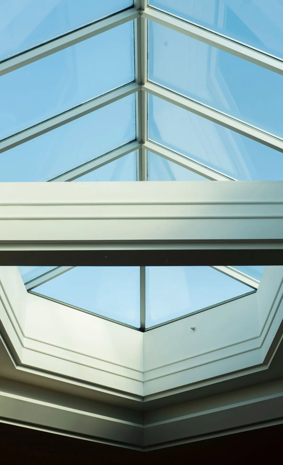 Skylight ceiling with blue glass panels and white framing, viewed from below