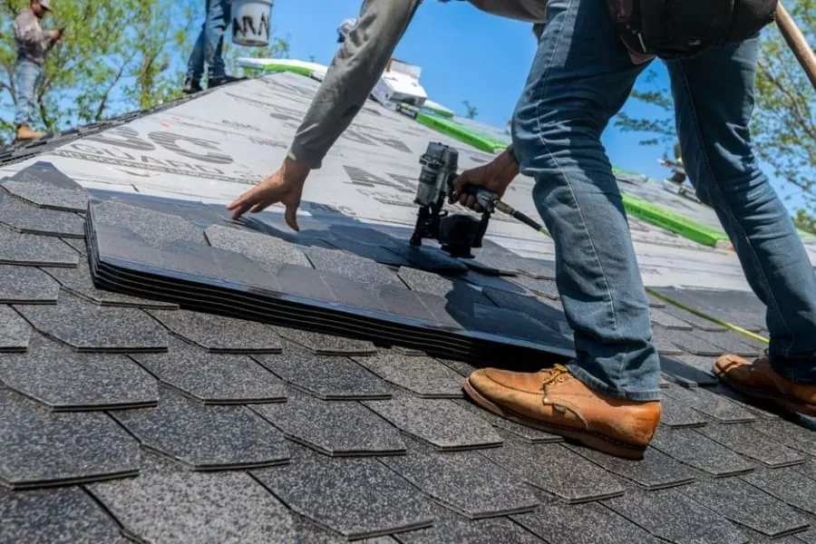 A roofer fixing slates with corrosion-resistant nails