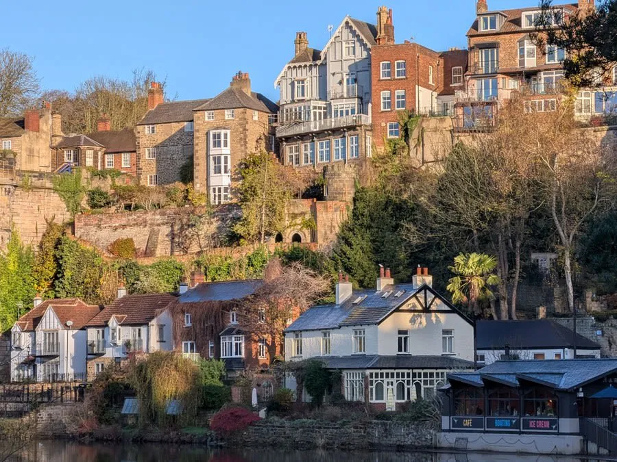 Hillside village of colorful houses and apartments above a river under a clear blue sky
