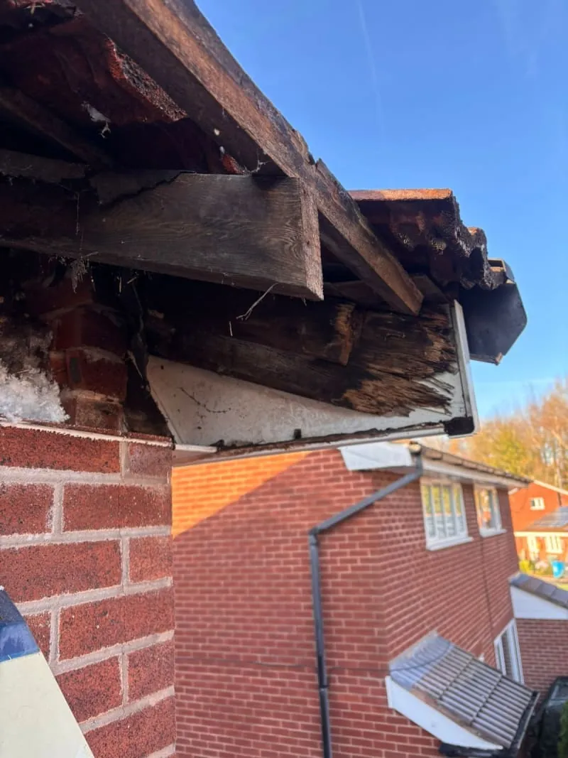 A low-angle view showing water damage on the roof eaves of a period brick property